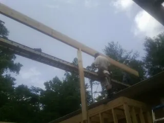 Carpenter setting a ridge beam over a new addition frame — Ice Dam Removal by Roofing Brothers in Bowman