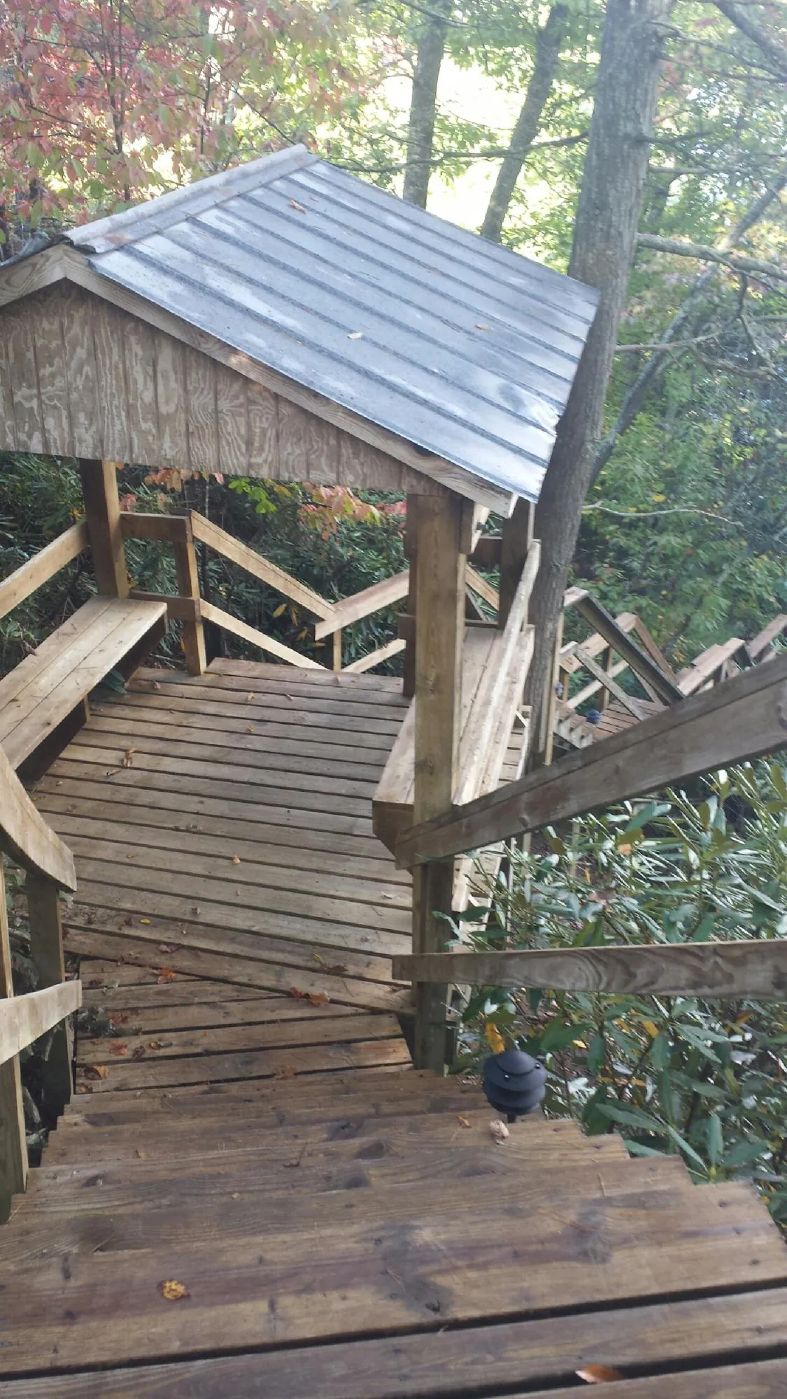 Metal roofed shelter over wooden steps on a wooded walkway — Skylight Repair & Installation work by our crew in Bowman